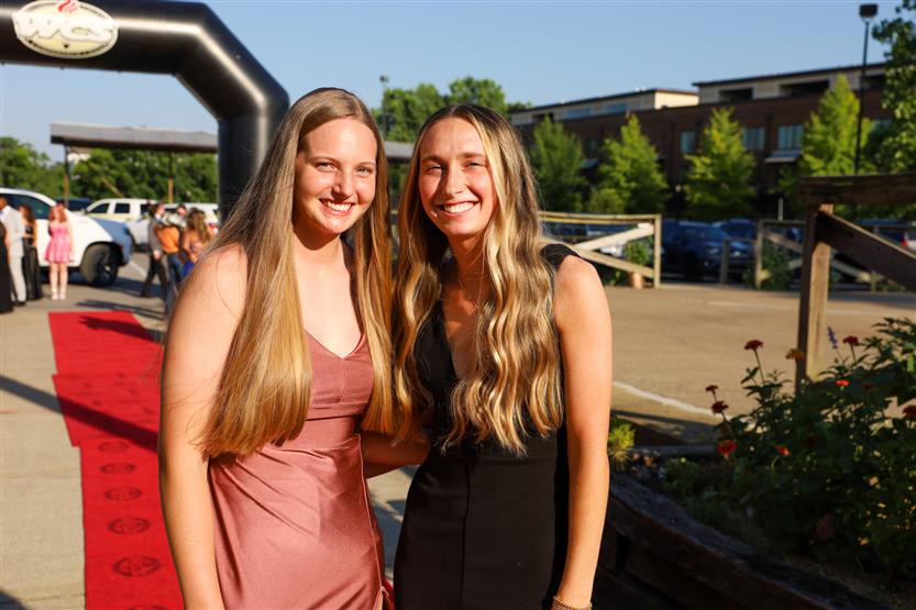 Two young women stand together and smile